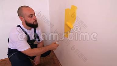 建筑工人和专业油漆工使用油漆滚筒刷油漆墙壁黄色。